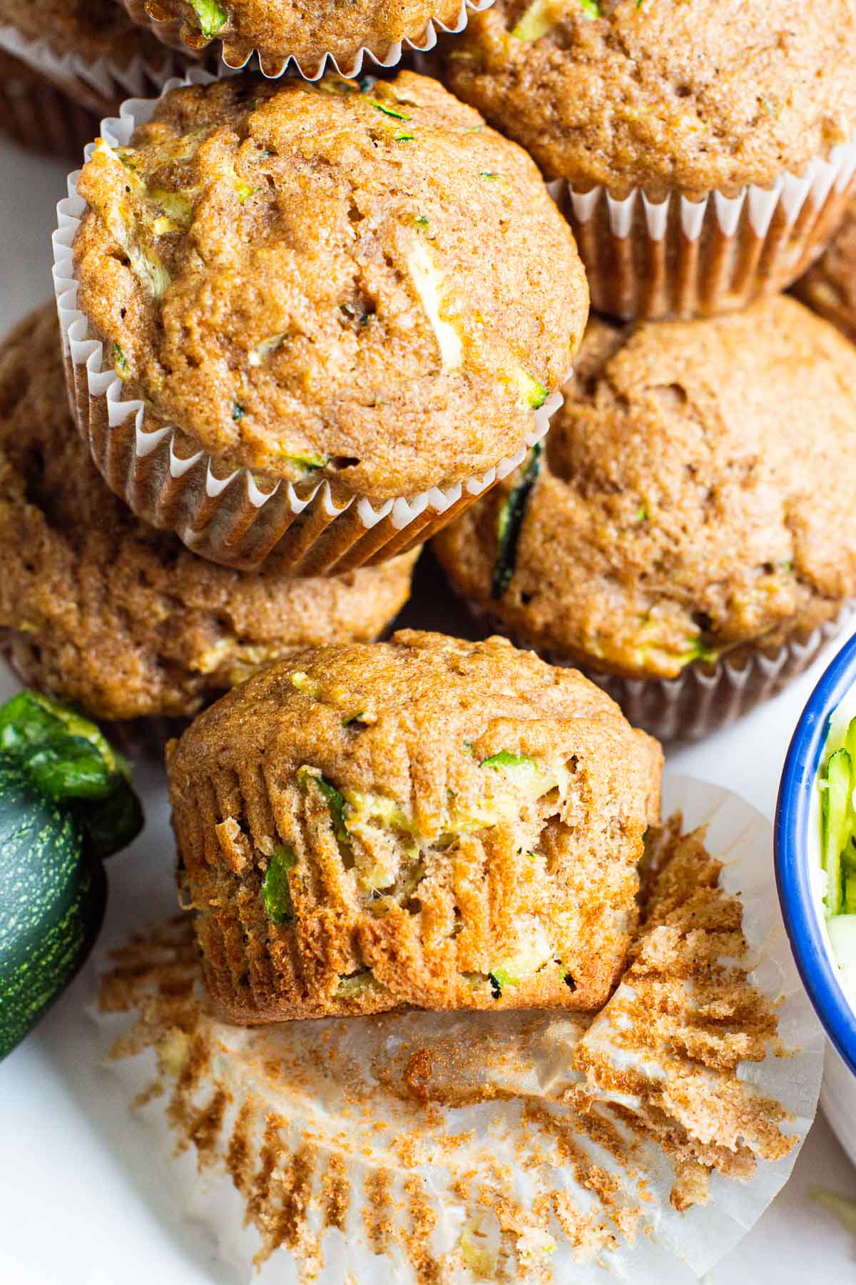 Healthy zucchini muffins stacked on top of each other with one unwrapped from liner.