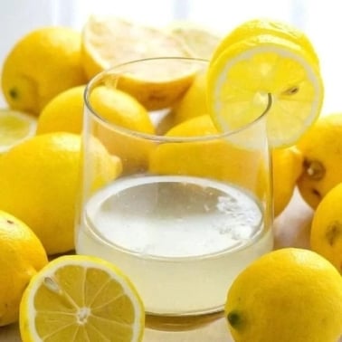 Lemon water in a glass with fresh lemons.