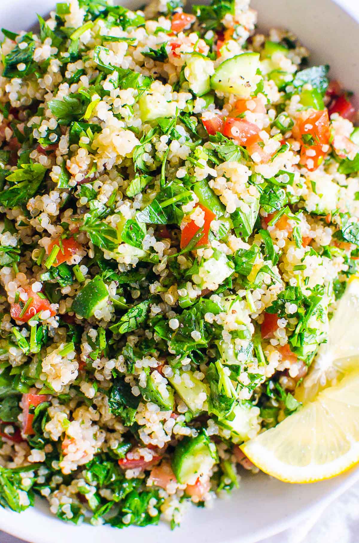 Quinoa tabbouleh salad on a white deep plate with lemon slices.