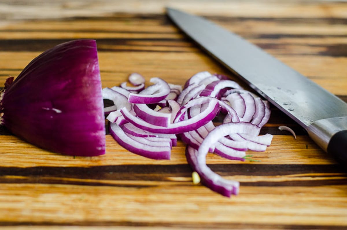 Sliced red onion on wooden cutting board.