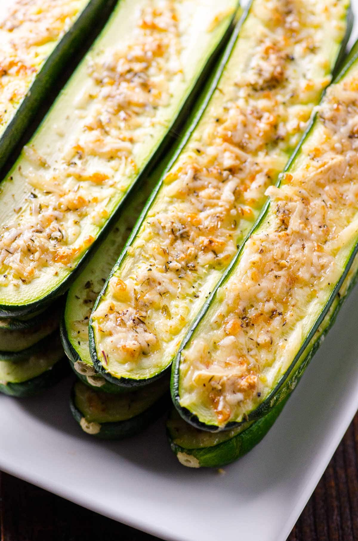Baked parmesan zucchini cut into halves with herbs stacked on top of each other.