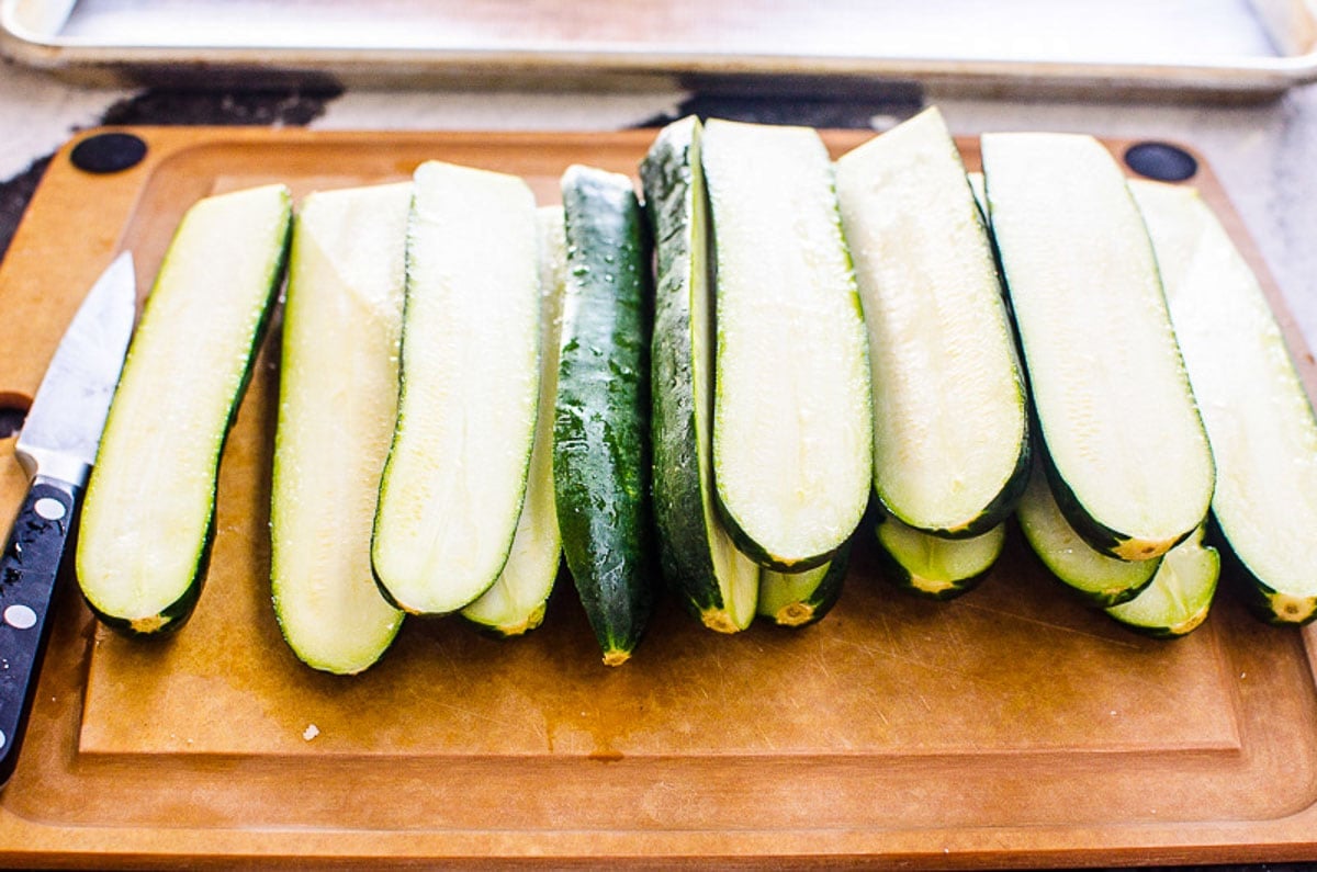 Zucchini cut in halves on cutting board.