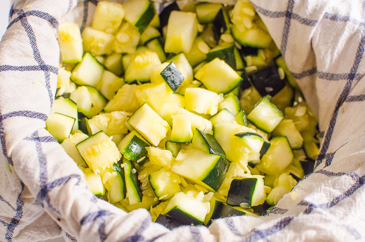 Chopped zucchini on a towel in colander.