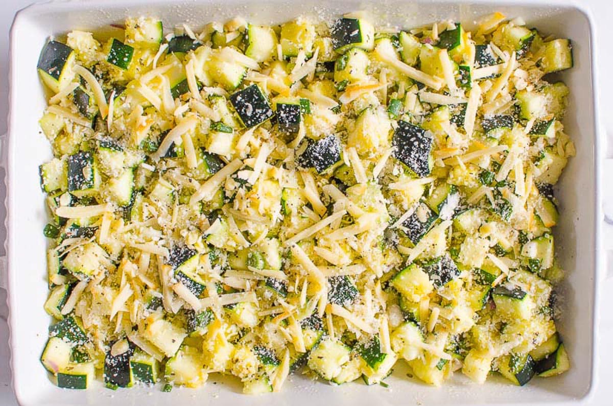 Chopped zucchini in a casserole dish sprinkled with cheese.