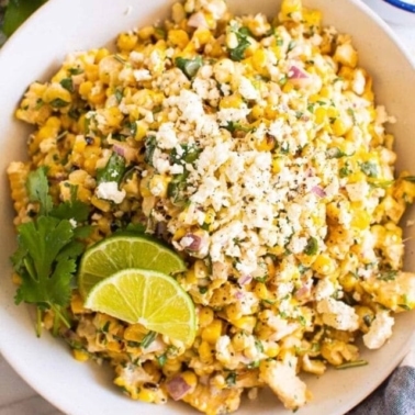 Mexican street corn salad in a bowl with lime and cilantro.