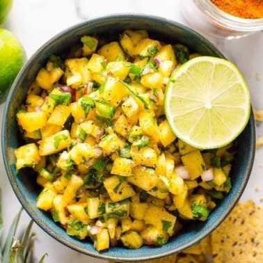 Pineapple salsa in a bowl with lime garnish.