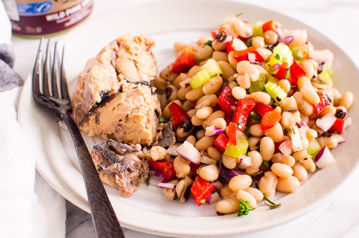 White bean salad served with canned salmon on white plate.