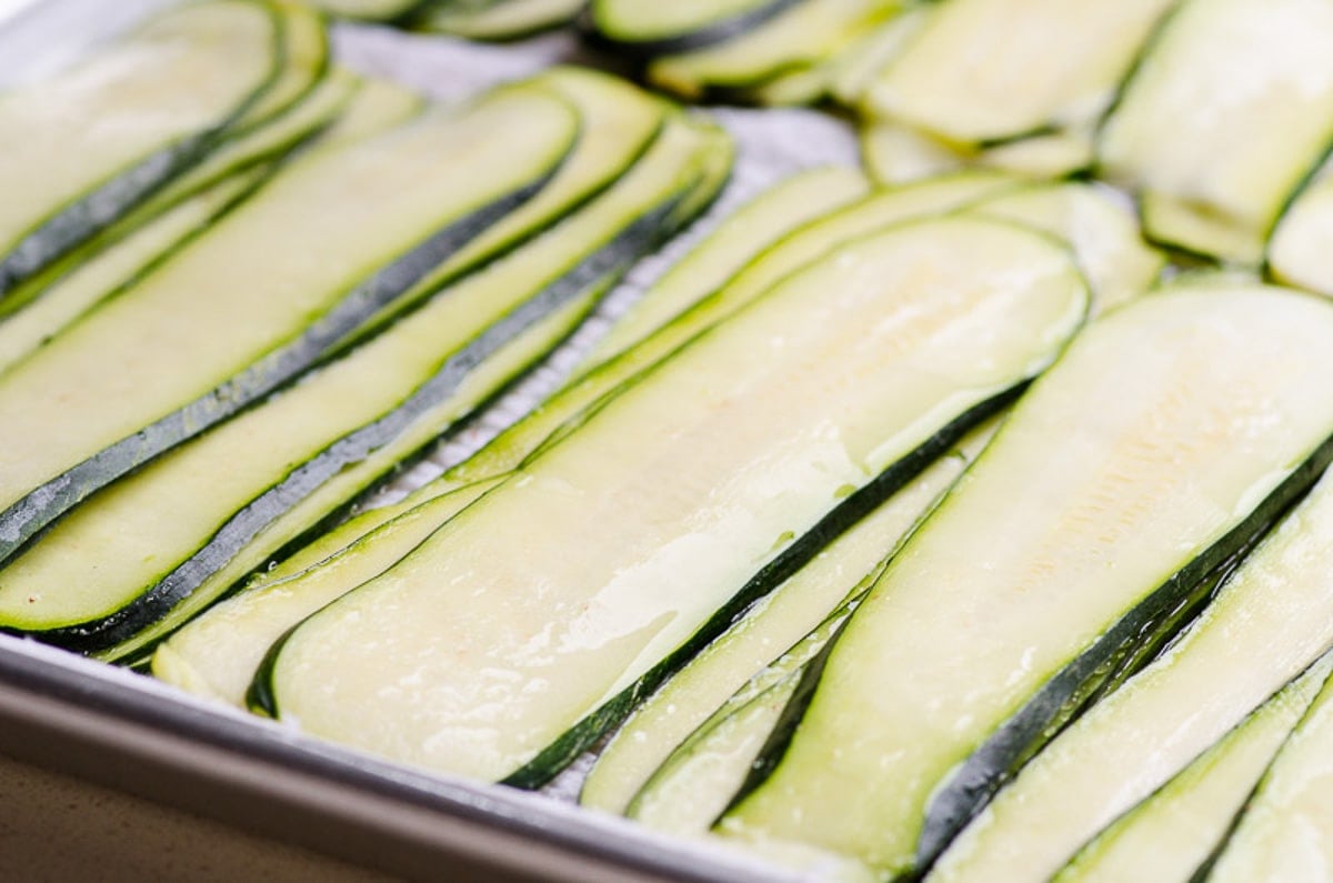 Sliced zucchini on baking tray sprinkled with salt.