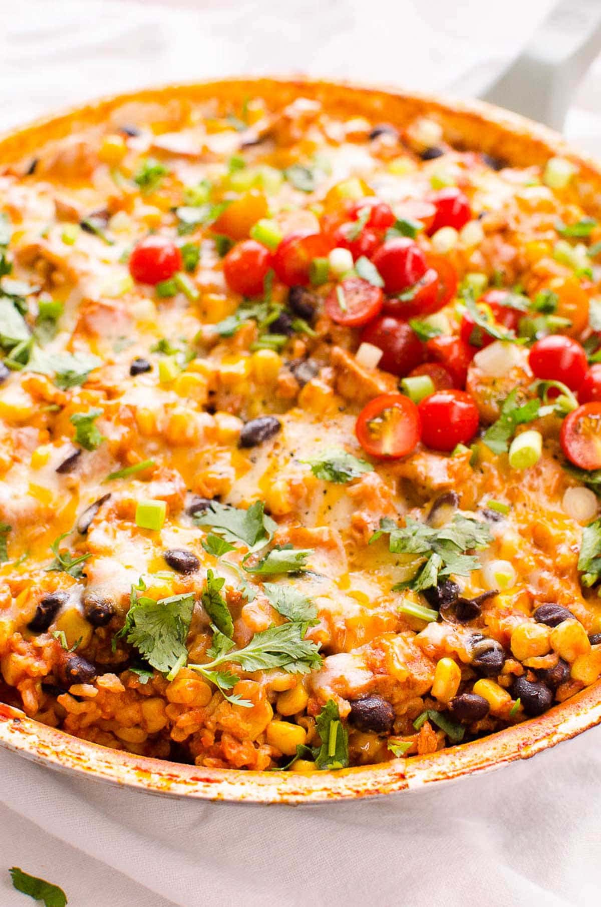 Chicken burrito skillet with cherry tomatoes, cilantro and green onion in skillet.