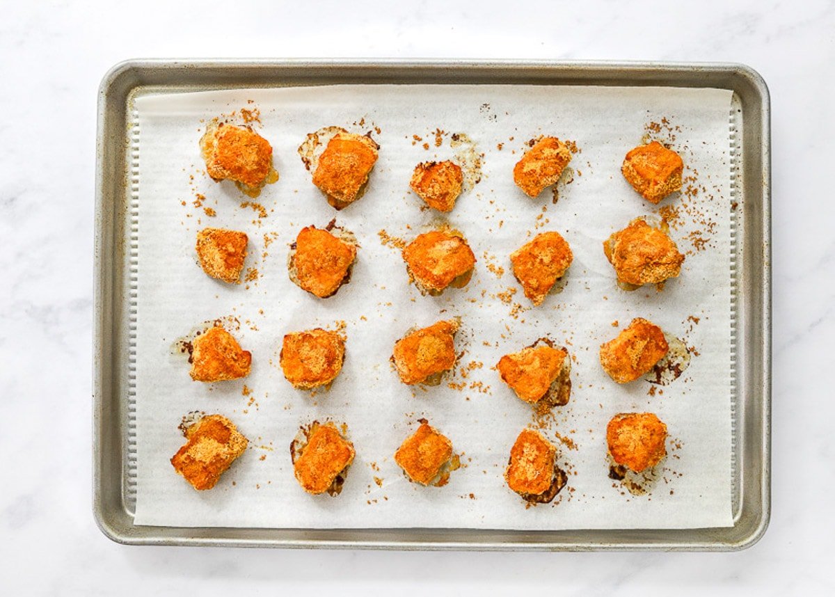 Baked healthy chicken nuggets on parchment lined baking sheet.