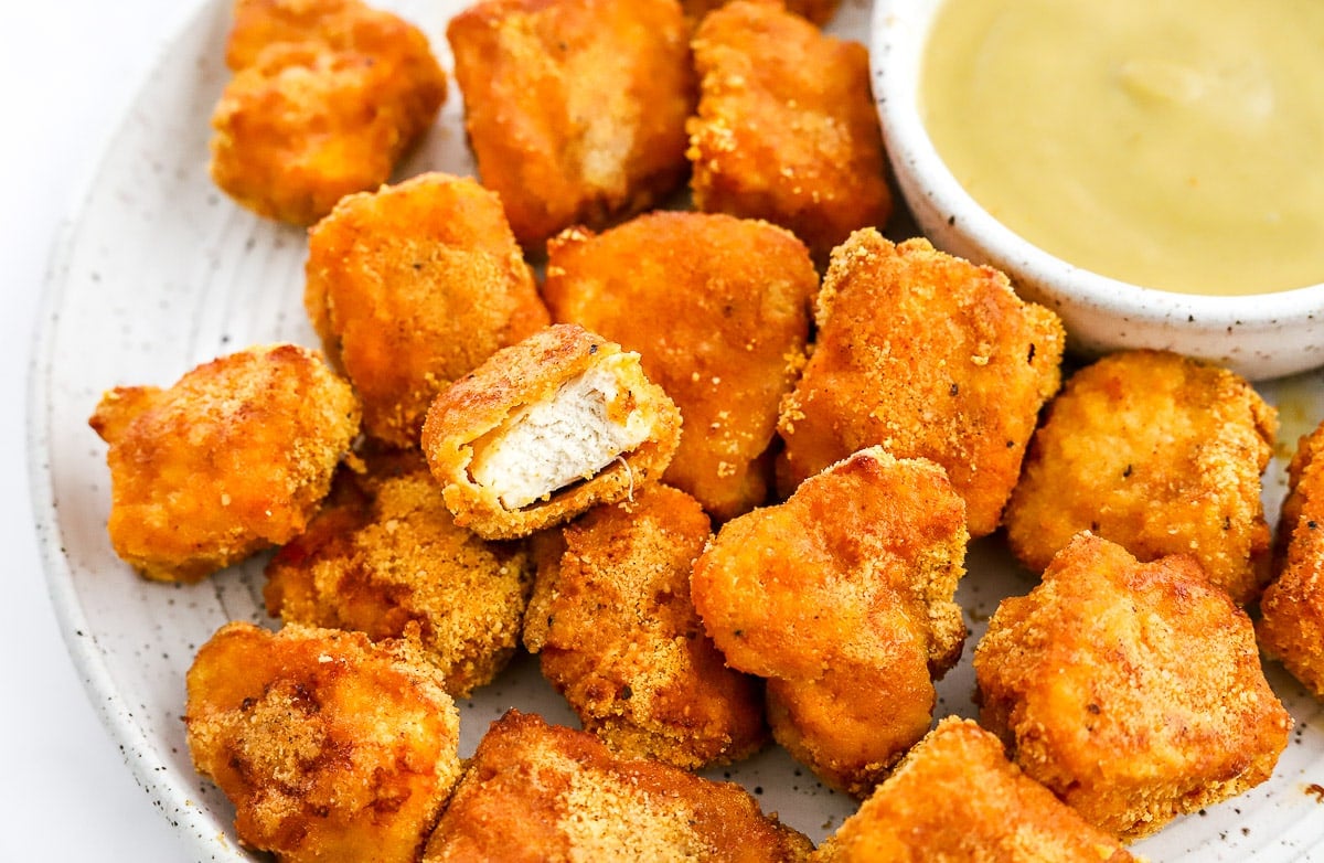 A plate of healthy chicken nuggets with a bite out of one.