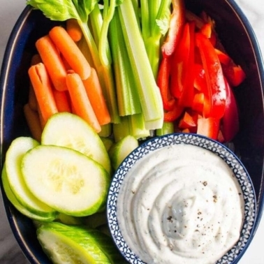 Healthy veggie dip in a bowl with cut fresh vegetables.