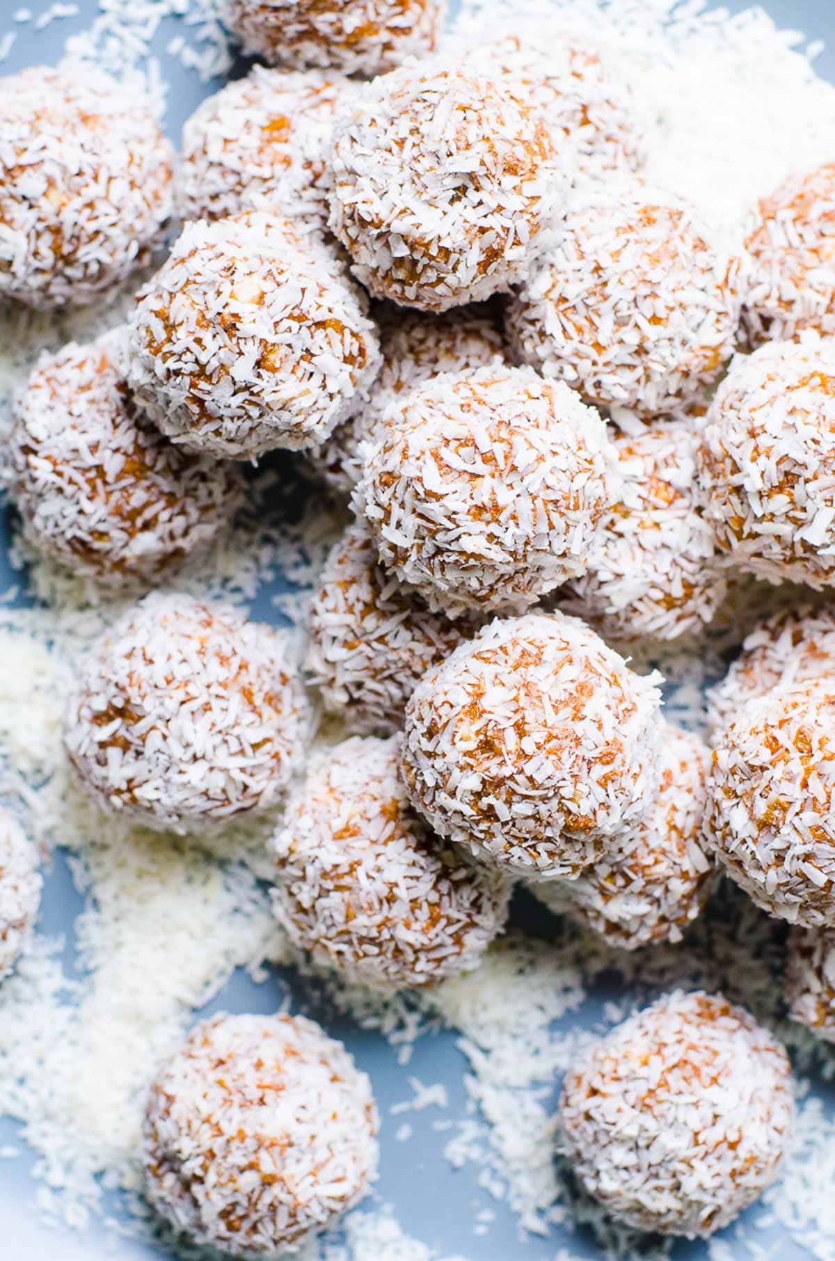 No bake protein balls rolled in coconut flakes on blue plate.