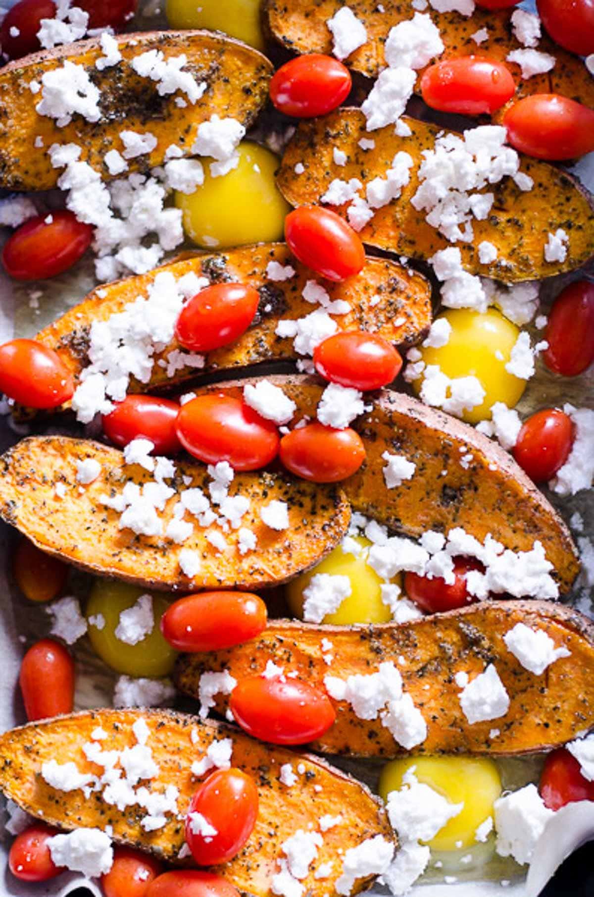 Cracked eggs in between sweet potatoes with grape tomatoes and crumbled feta on top.