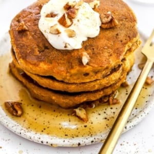 Healthy pumpkin pancakes on a plate with pecans and syrup.
