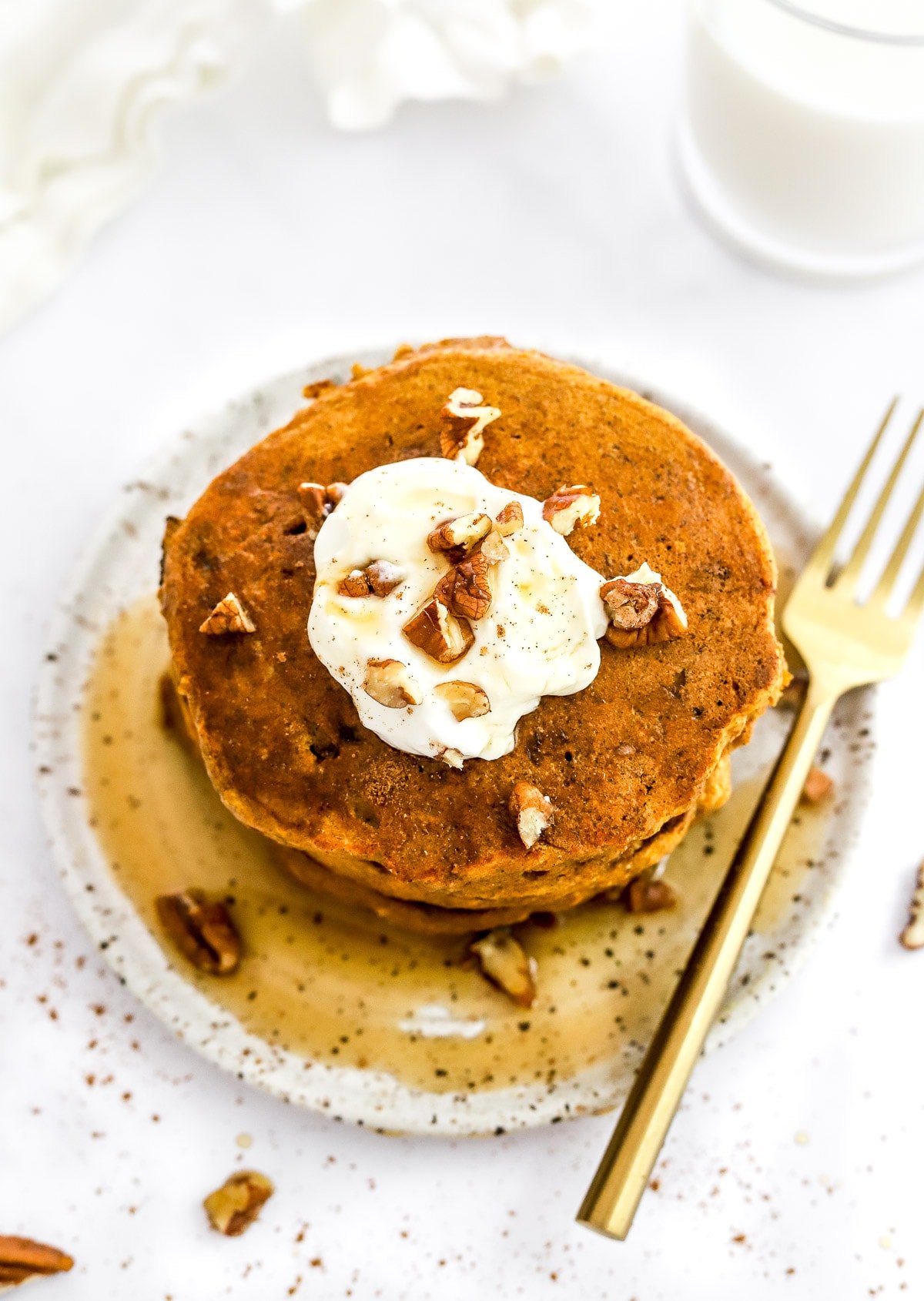 A stack of healthy pumpkin pancakes on a plate with toppings.