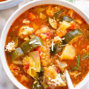 Instant Pot vegetable soup in a white bowl with spoon.