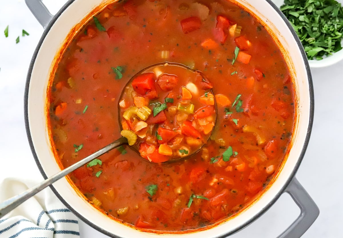 A pot with vegetarian pasta fagioli in a ladle.