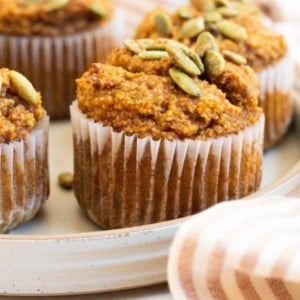 Almond flour pumpkin muffins on a plate garnished with pumpkin seeds.