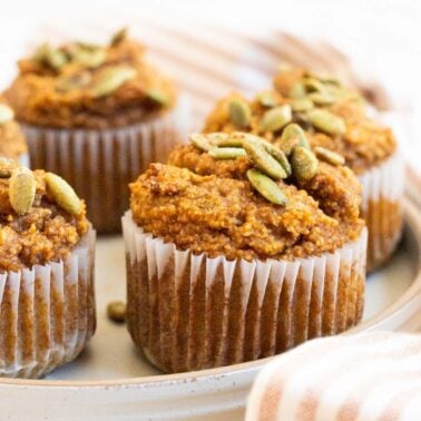 Almond flour pumpkin muffins garnished with pumpkin seeds on a plate.
