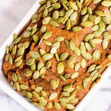 Healthy pumpkin bread studded with pepitas in a loaf pan.