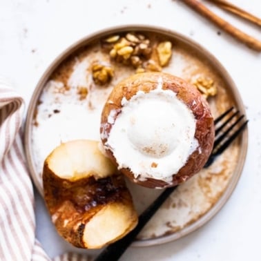 Healthy baked apples on a plate one topped with Greek yogurt.