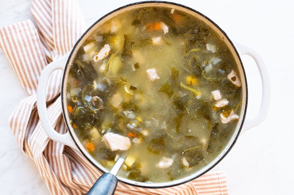 Green borscht in dutch oven with ladle.