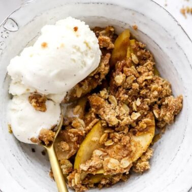 Healthy apple crisp in a bowl with ice cream.