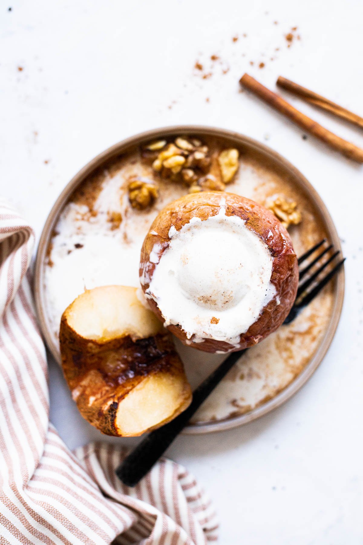 Healthy baked apples on a plate for serving, one topped with vanilla ice cream.