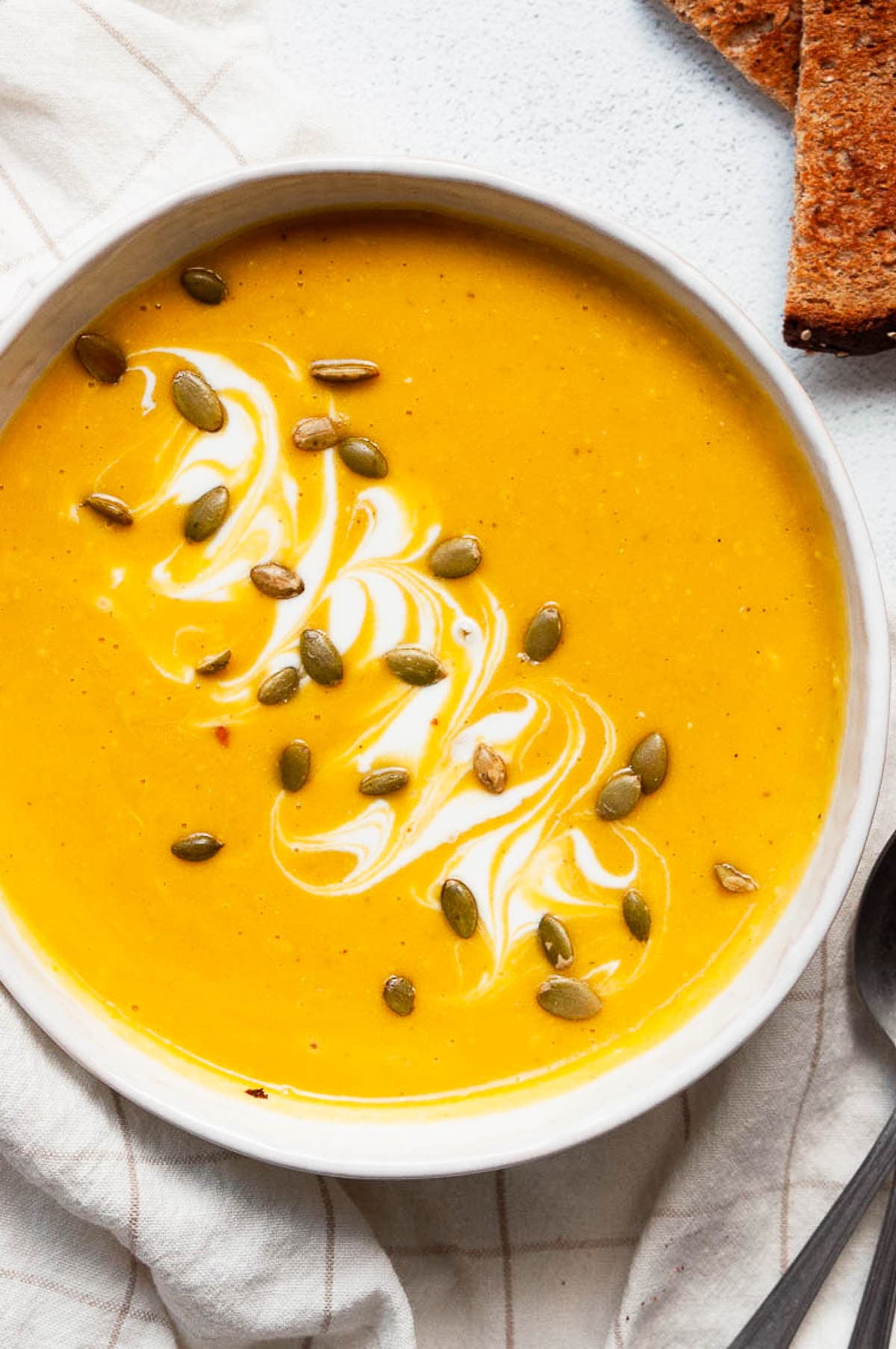 Healthy butternut squash soup with pumpkin seed garnish and yogurt swirl.