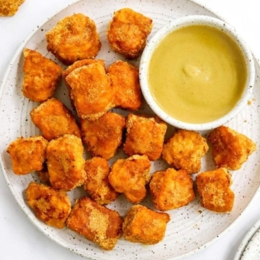 Healthy chicken nuggets on a plate with mustard dipping sauce.