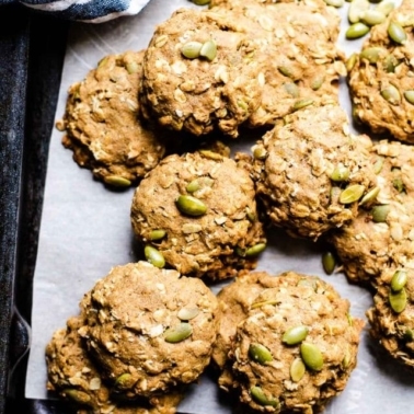 Healthy pumpkin cookies on parchment lined baking tray with pumpkin seeds.