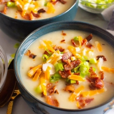 Instant Pot potato soup in two bowls with cheese and bacon toppings.