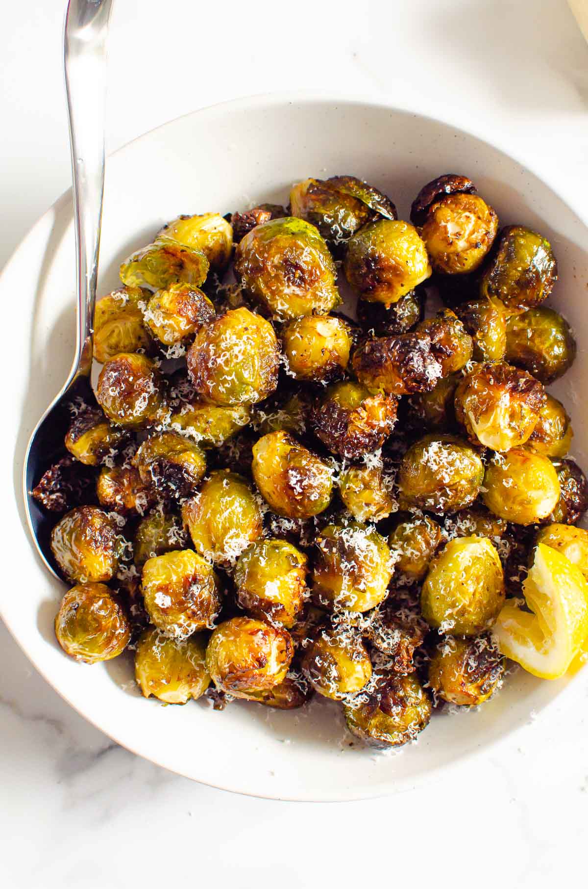 Parmesan roasted brussels sprouts in a serving bowl with spoon.