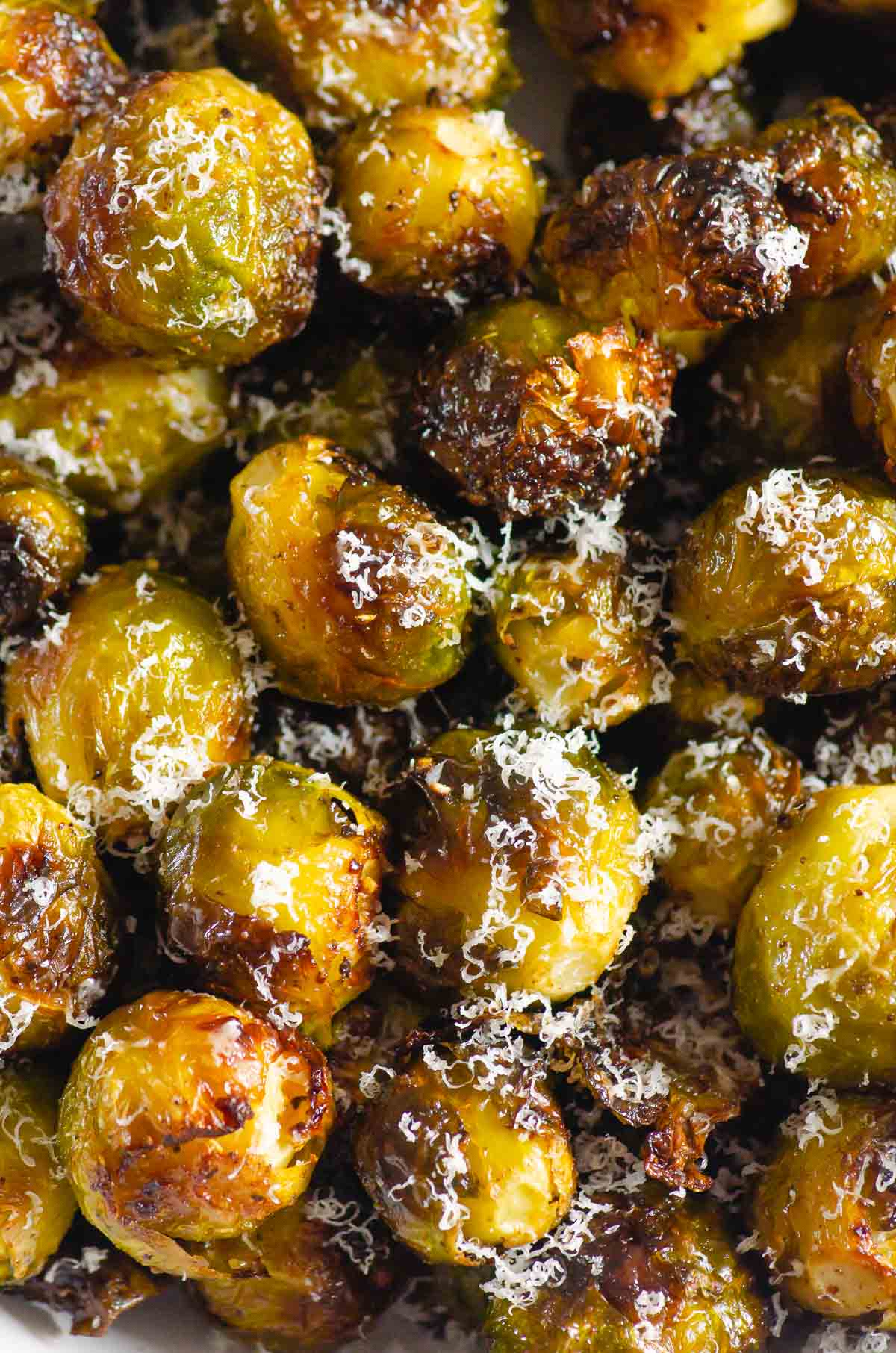 Close up of roasted Brussels sprouts with parmesan cheese and a lemon wedge.