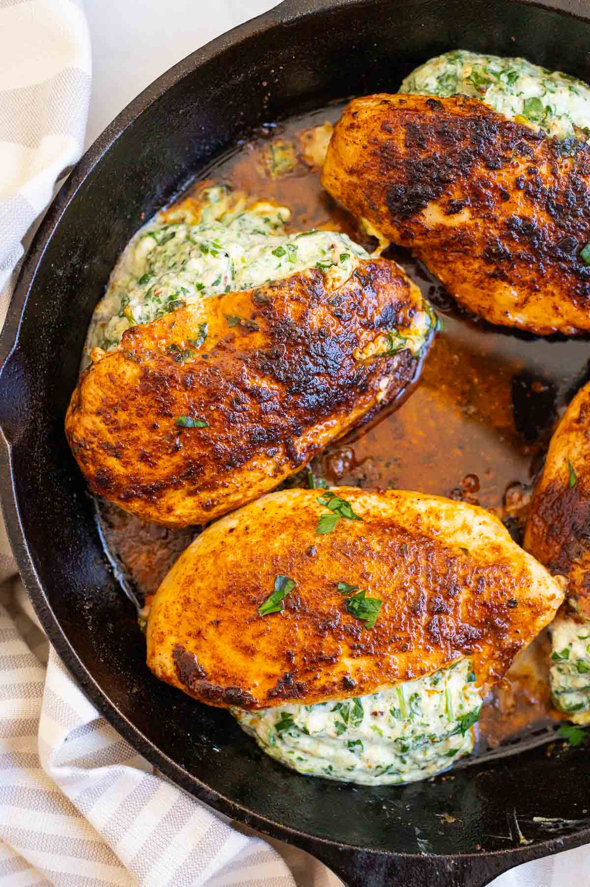 Spinach stuffed chicken breasts in cast iron skillet.