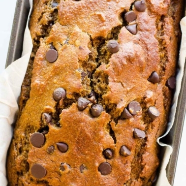 Healthy pumpkin chocolate chip bread in a loaf pan with parchment paper.