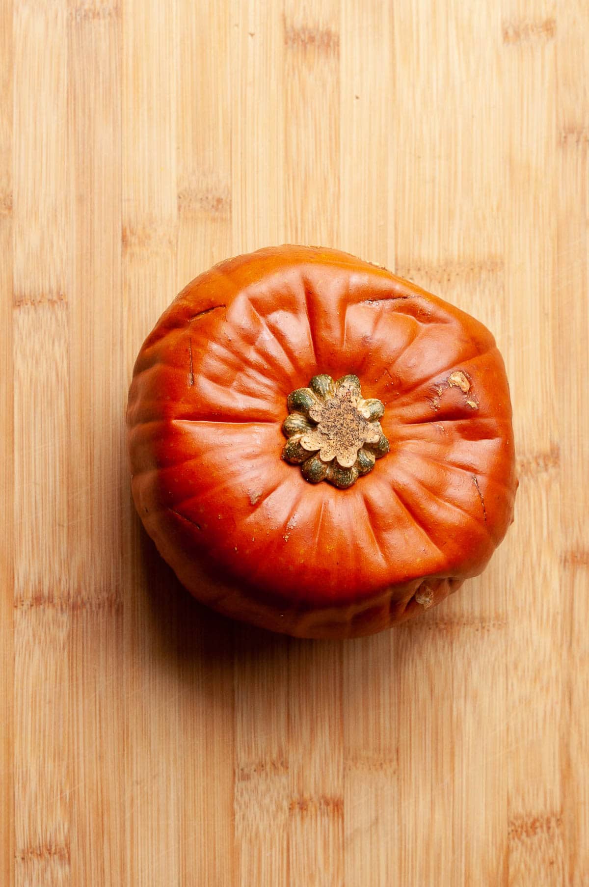 Whole roasted sugar pumpkin on a cutting board.