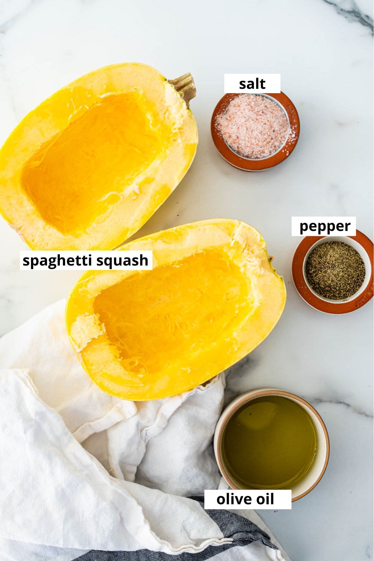 Cut in half spaghetti squash, salt, pepper, olive oil and towel on a counter.