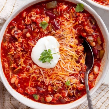 Turkey chili recipe in a bowl with Greek yogurt, cilantro and cheese.