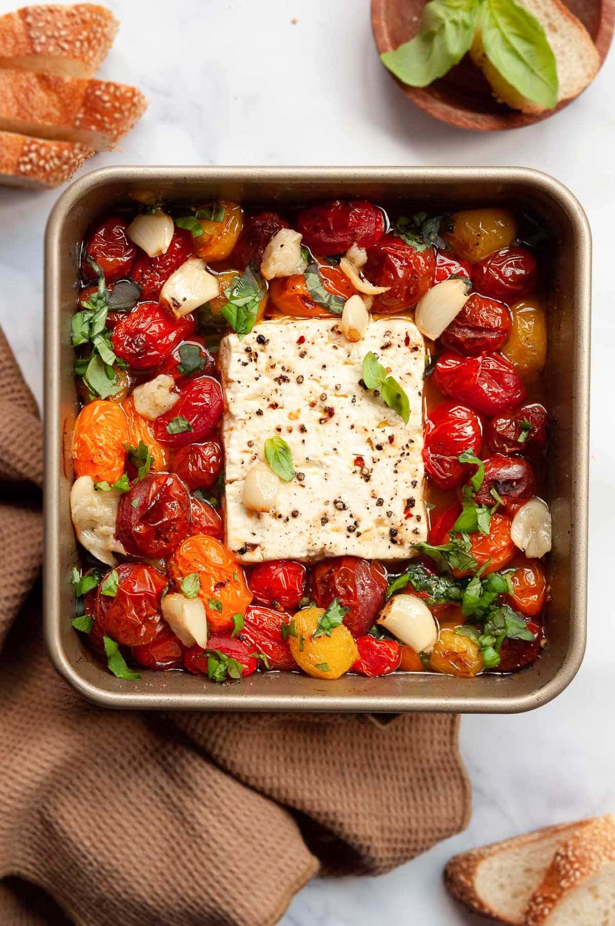 Baked feta dip with tomatoes, garlic and basil in square baking dish.