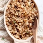 Person holding wooden spoon in a dish with cauliflower stuffing.