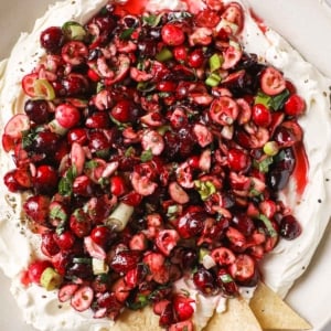 Cranberry jalapeno dip with cream cheese served in a bowl with tortilla chips.