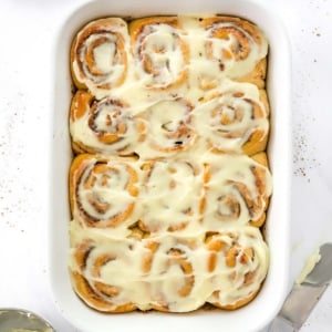 Healthy cinnamon rolls with cream cheese frosting in baking dish.