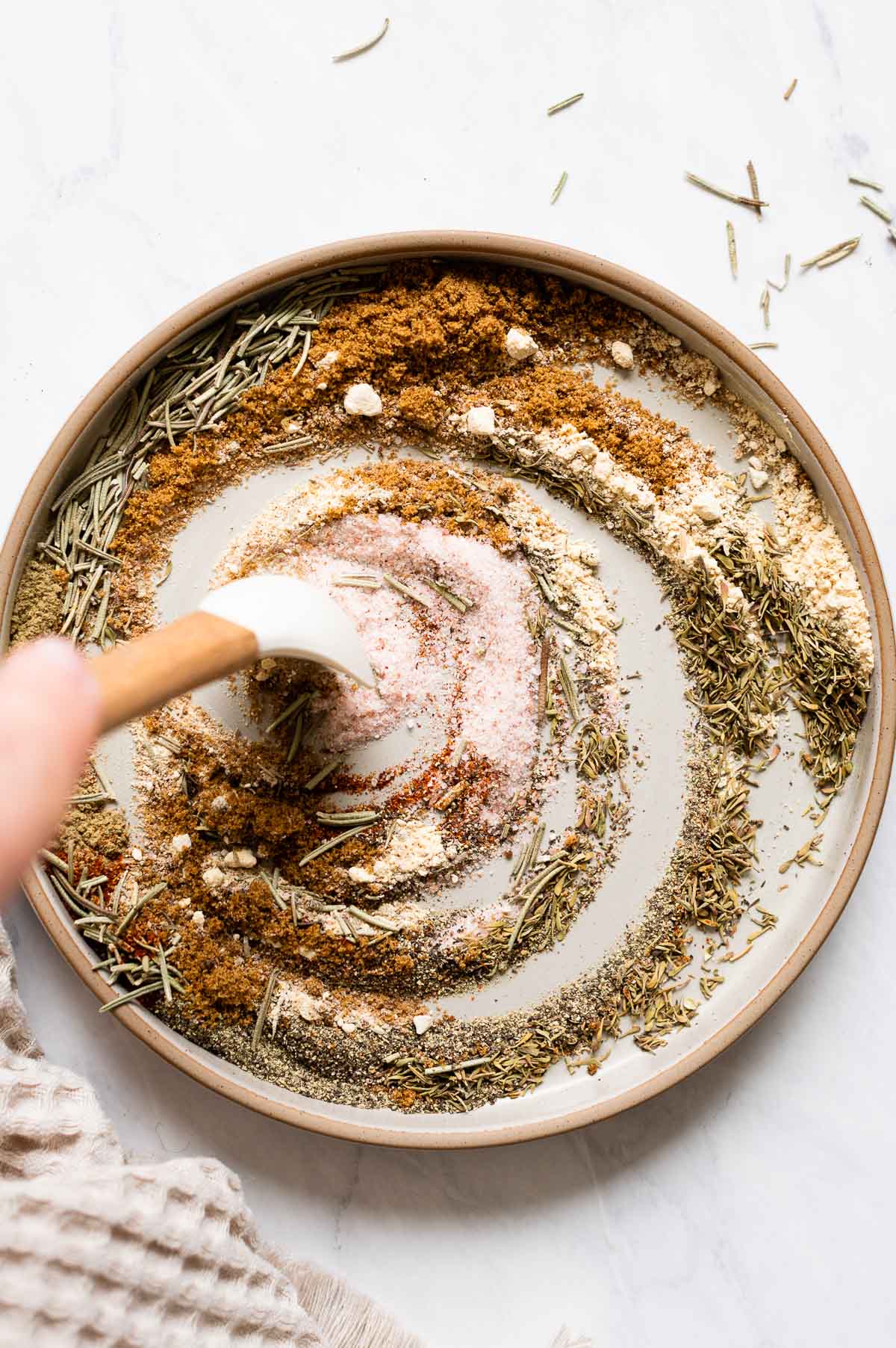 Person stirring turkey breast rub with a spoon on a plate.