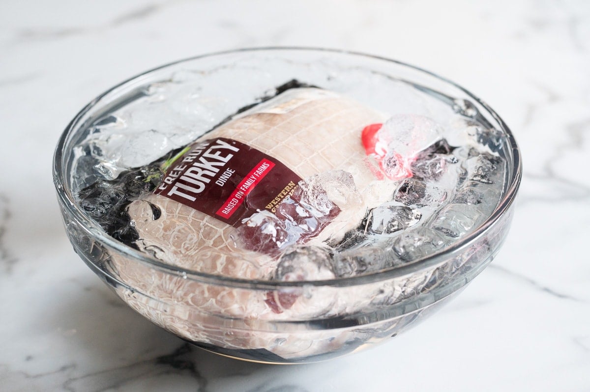 Frozen turkey breast thawing in cold ice bath.