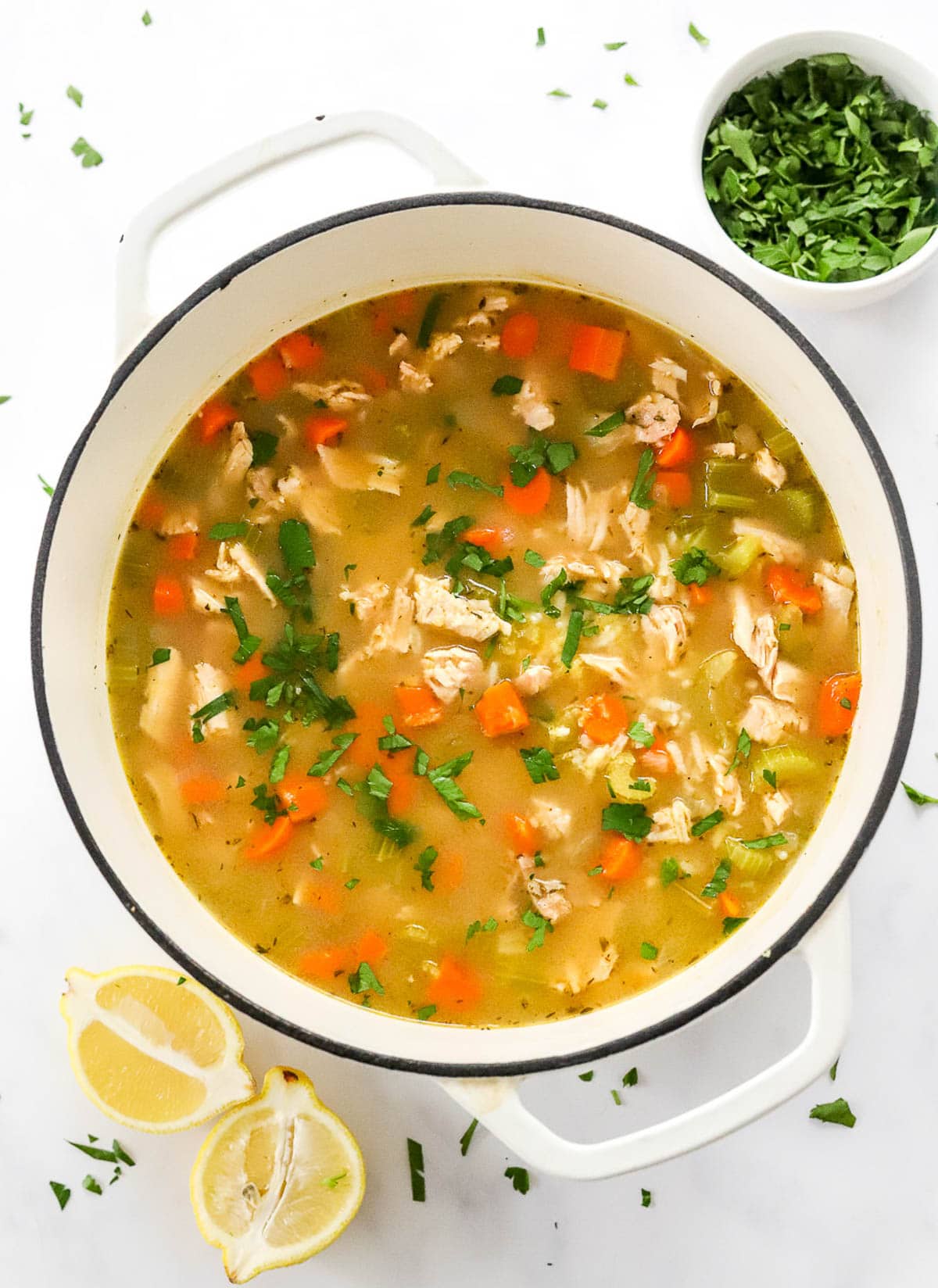 Turkey and rice soup with carrots, celery and parsley in white pot.