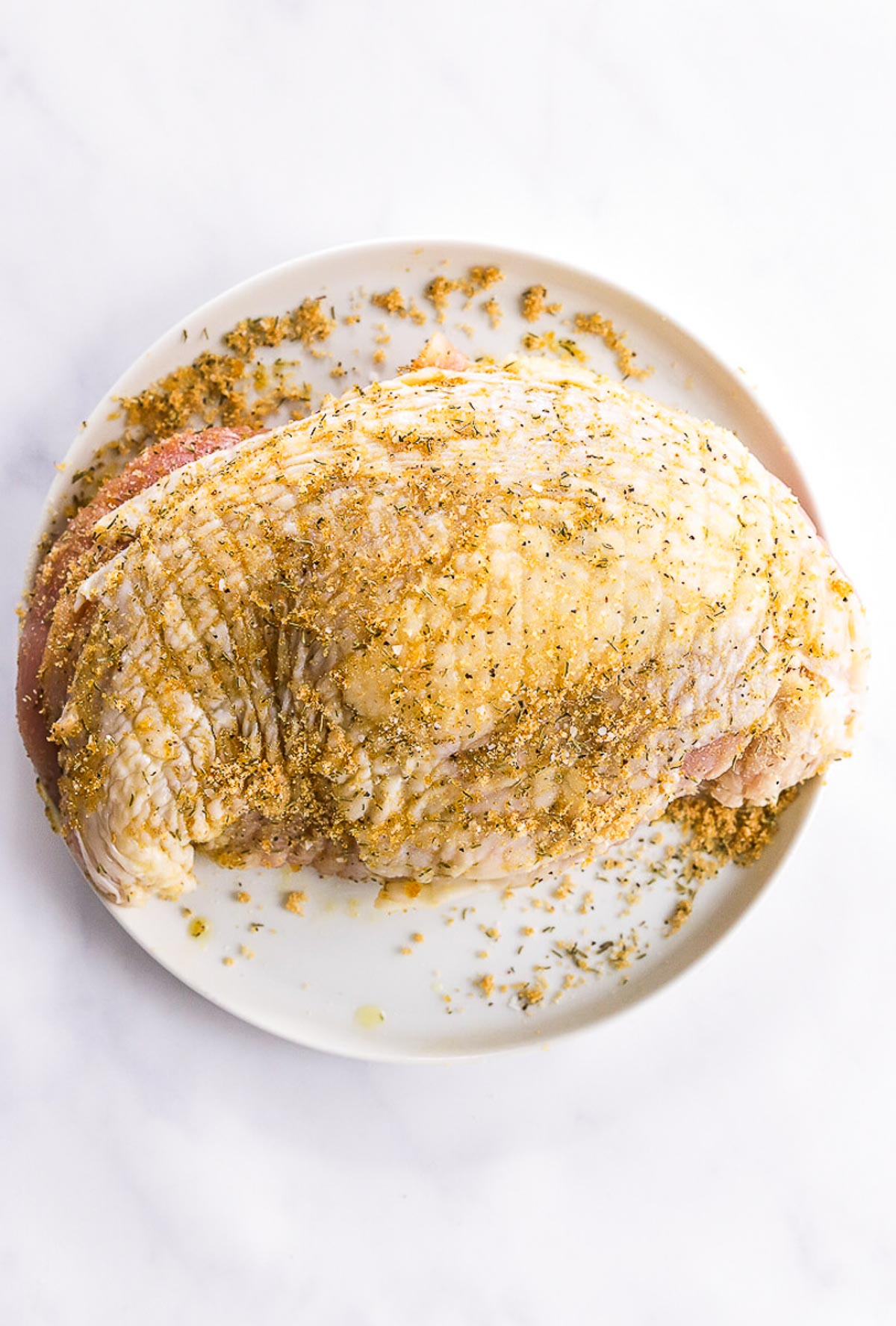 Turkey breast seasoned with dry rub on a plate.