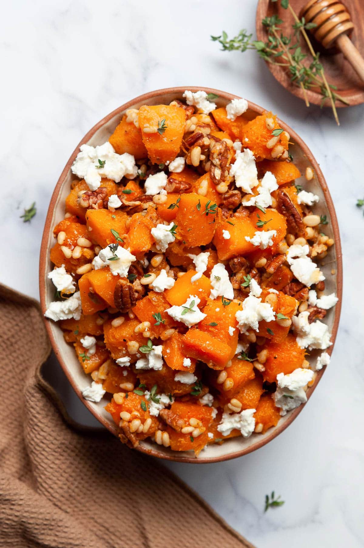 Sauteed butternut squash with pine nuts and goat cheese in a bowl.