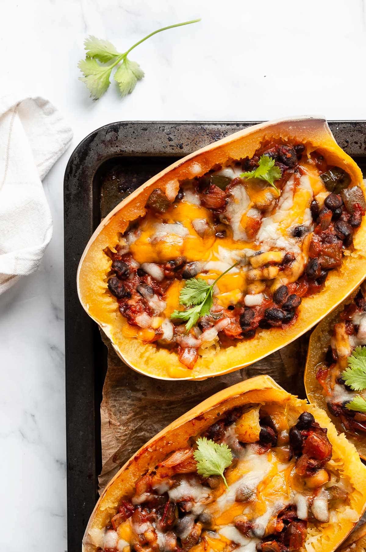 Tex Mex stuffed spaghetti squash halves on baking sheet lined with parchment paper.